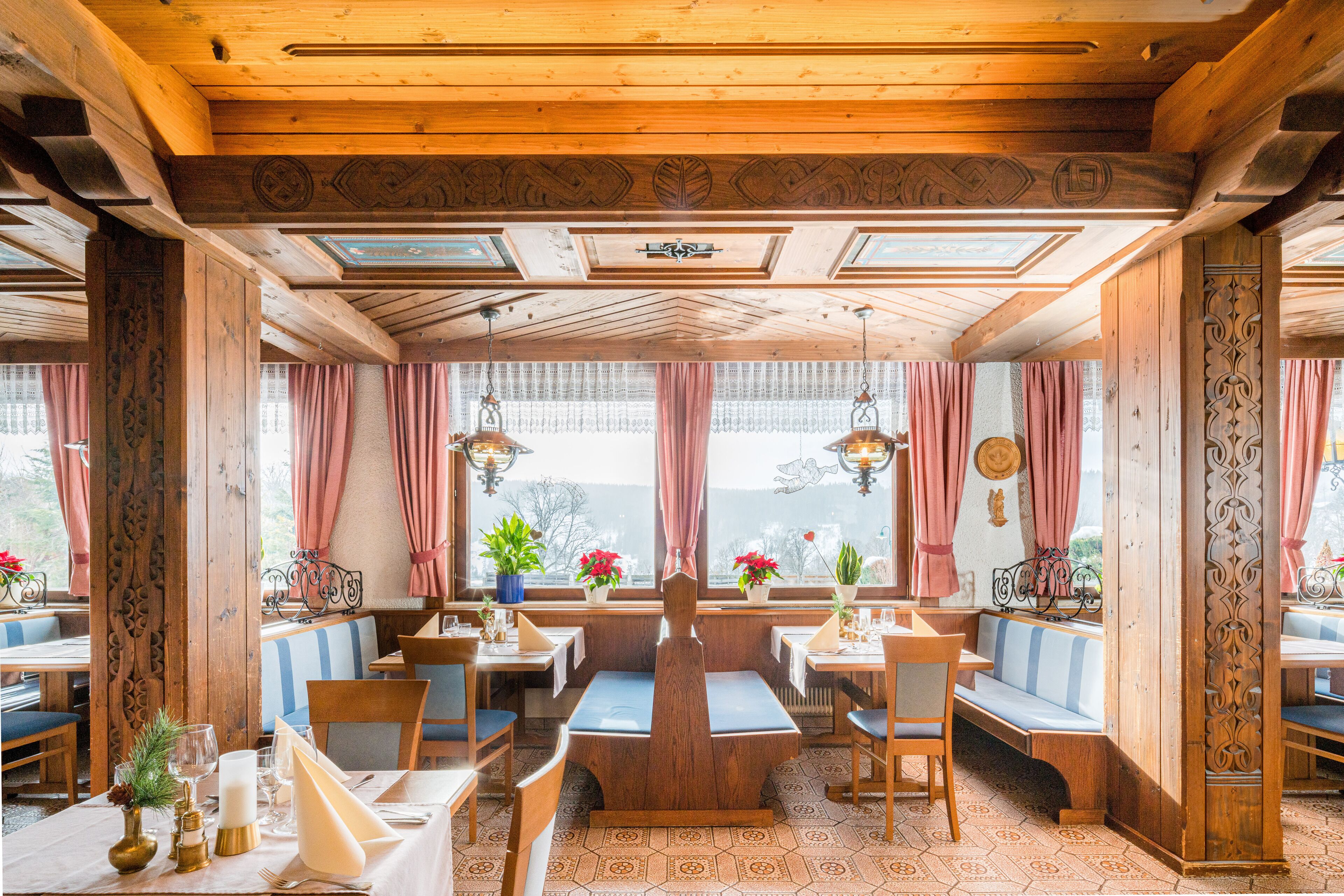 Un restaurante con interiores de madera, ventanas amplias con cortinas y una zona de estar central.