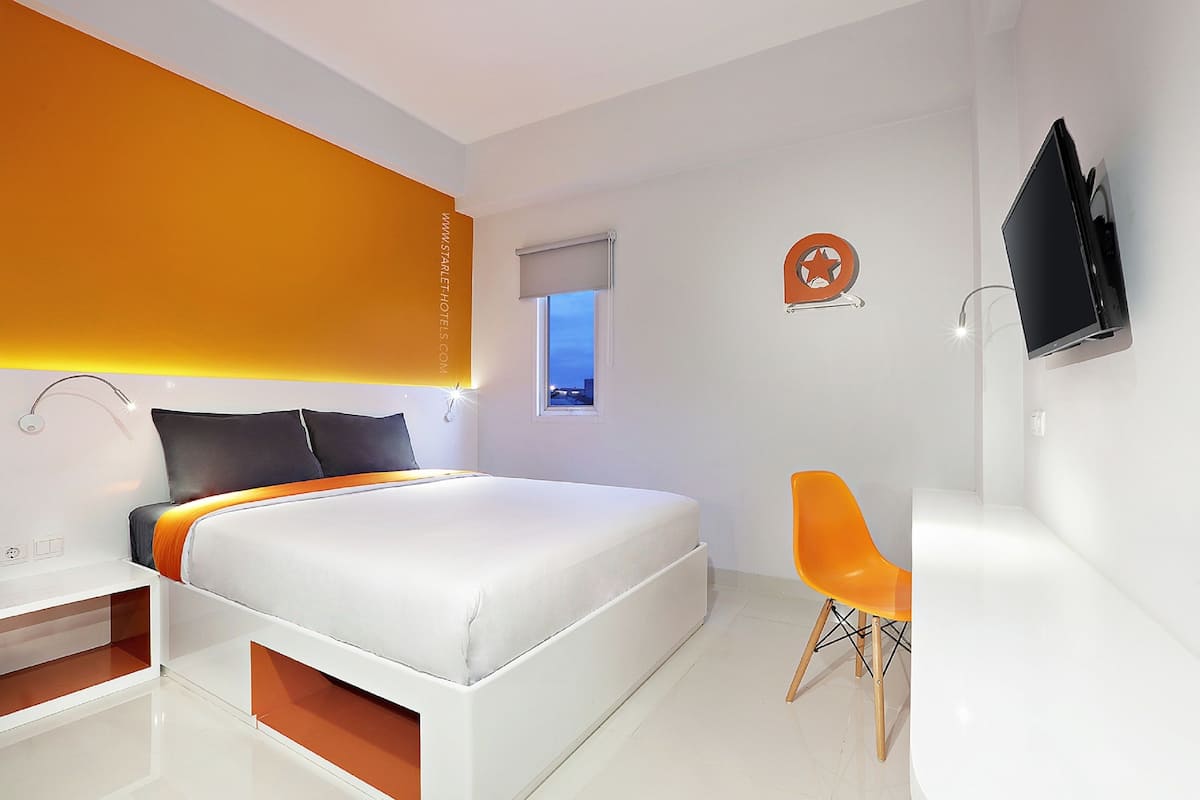 A modern bedroom with a large bed, a desk, and a TV.