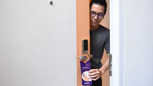 A person holding a door handle in a room with a white door and an orange wall. - Starlet Hotel Serpong (South Tangerang)