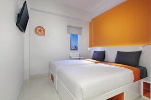 A modern hotel room with a large bed, a TV mounted on the wall, a window with a city view, and a website address on the wall. - Starlet Hotel Serpong (South Tangerang)