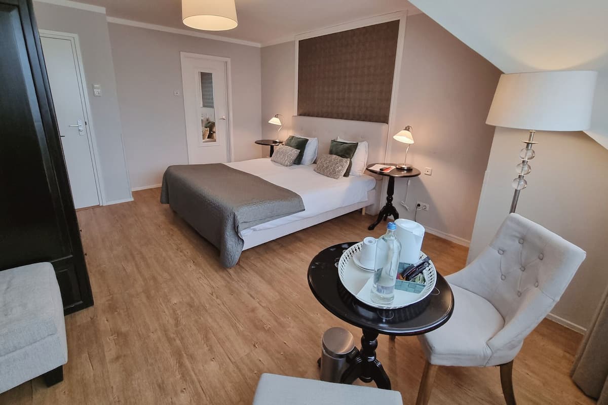 Una habitación de hotel moderna con una cama bien hecha, una mesa de comedor con una bandeja de alimentos para el desayuno, una silla y una lámpara.