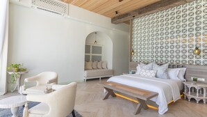 Een moderne slaapkamer met een groot bed, een bank, een eettafel en een behang met een patroon.