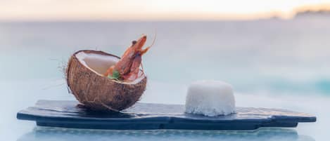 A dining table with a coconut shell containing a shrimp and a mound of white rice.