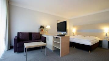 Une chambre d’hôtel avec un lit, un bureau avec un ordinateur, un canapé et une petite table.