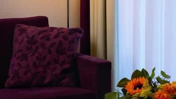 A room with a sofa, a table with a candle, and a vase of flowers.