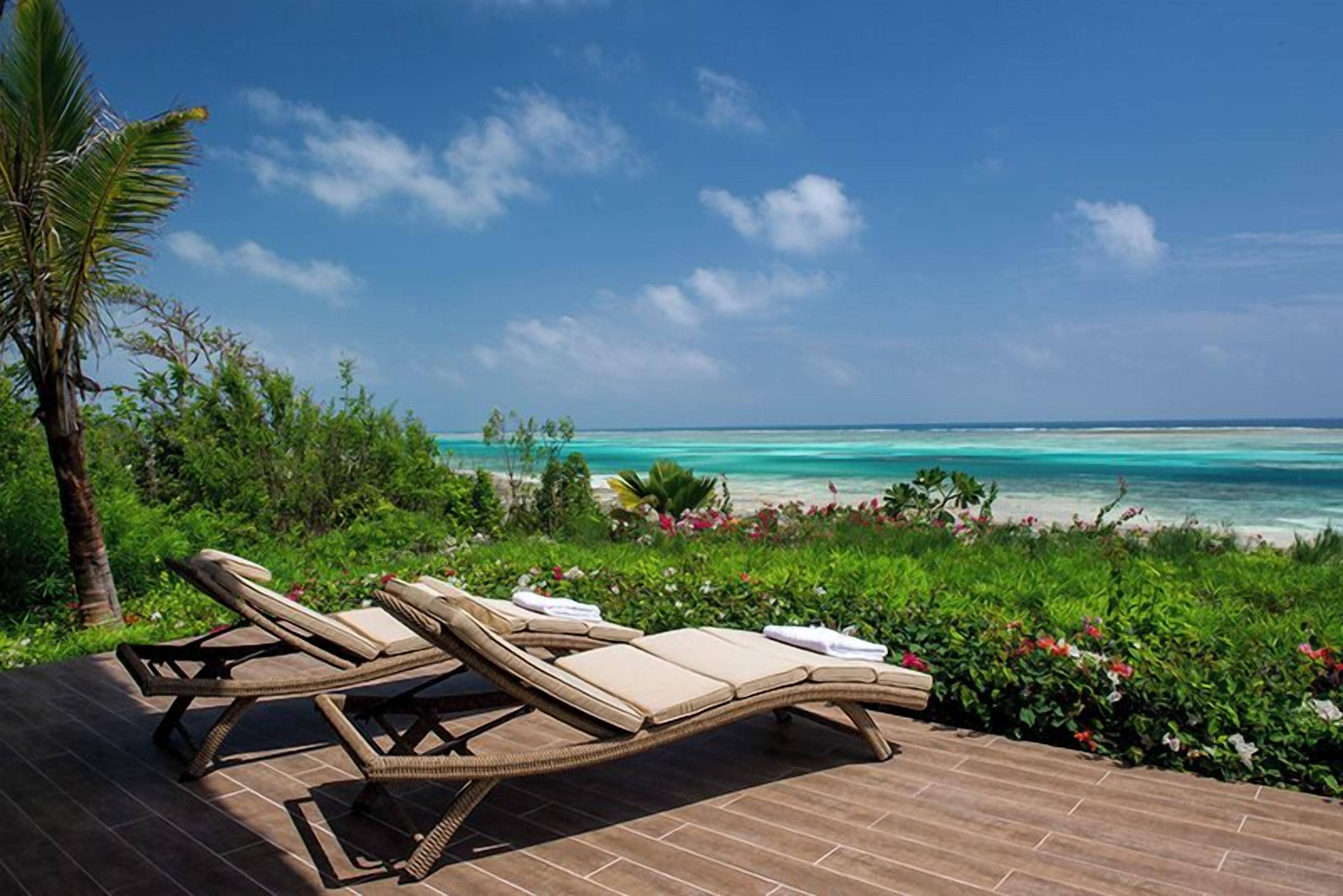 A poolside area with lounge chairs and a view of the ocean.