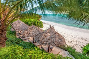 Privat strand, hvit sand, solsenger og parasoller