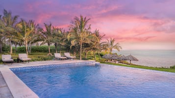 Una piscina al aire libre, sillones reclinables de piscina