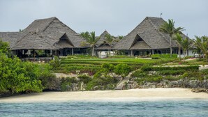 A resort with thatched-roof buildings, a beach, and a landscaped garden. - Zawadi Hotel Zanzibar - All Inclusive (Dongwe)