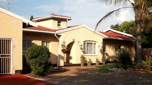 Ein Wohnhaus mit befestigter Auffahrt, rotem Teppich und kleinem Garten mit Topfpflanzen.
