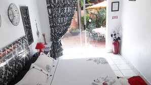 Ein Schlafzimmer mit einem Bett, einer roten Lampe, einem gemusterten Vorhang und Blick auf die Außenpatio.