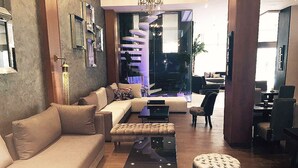 A modern living room with a sofa, ottoman, and a coffee table. There is a dining area with chairs and a table. - The Seven Hotel and Spa (Casablanca)