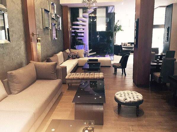 A modern living room with a sofa, ottoman, and a coffee table. There is a dining area with chairs and a table.