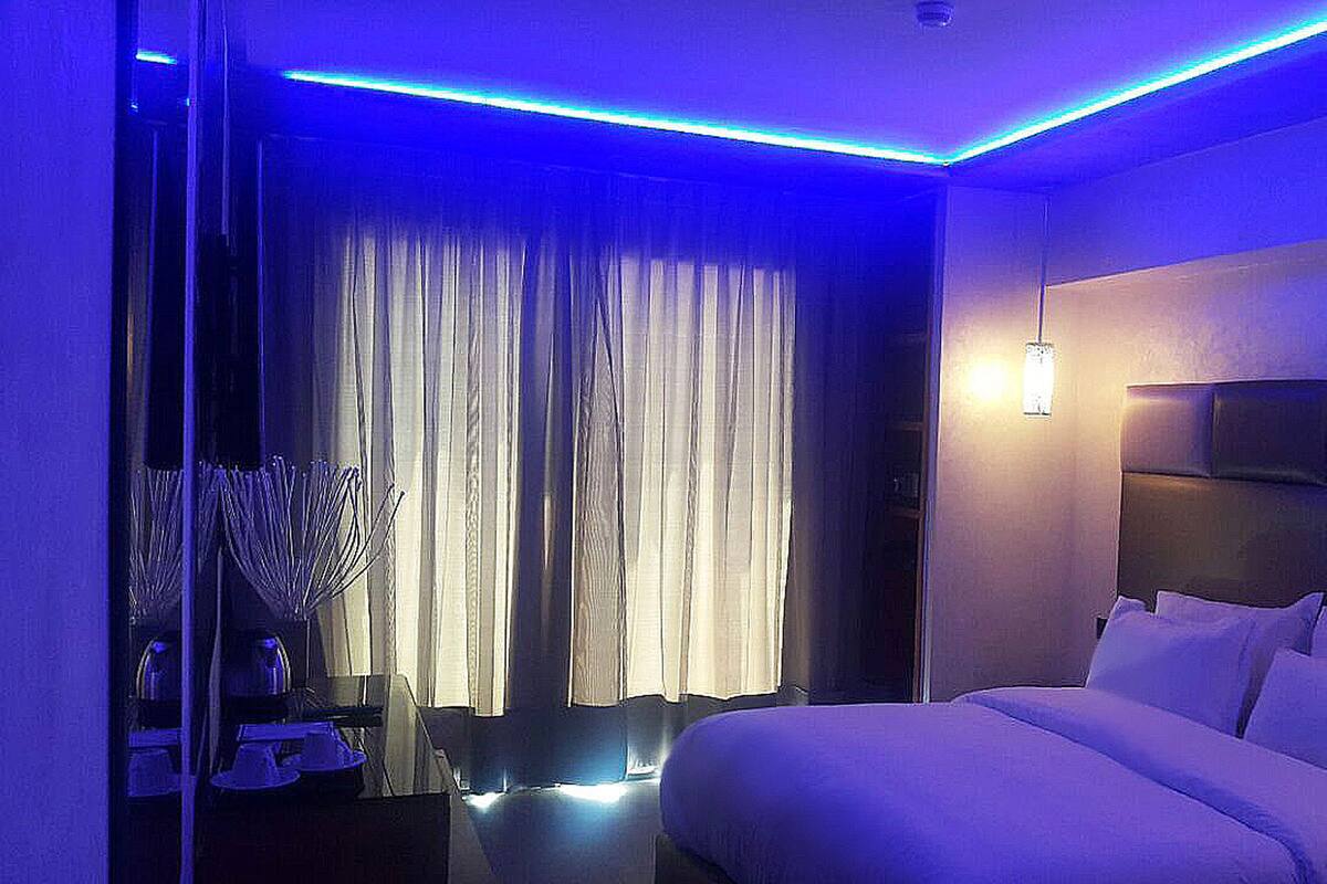 A modern hotel room with a large bed, a bedside table, and a window with curtains.