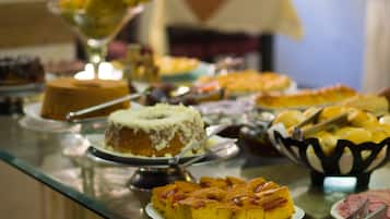 Mesa de buffet com diversos doces, incluindo bolos e frutas.