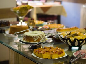 A buffet table with various desserts including cakes and fruit. - Hotel Estrela do Sul (Curitiba)