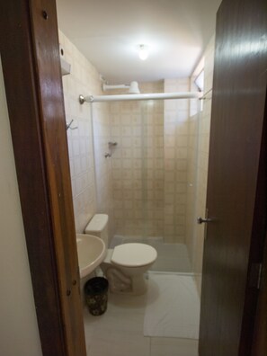 A small bathroom with a toilet, sink, and shower area. - Hotel Estrela do Sul (Curitiba)