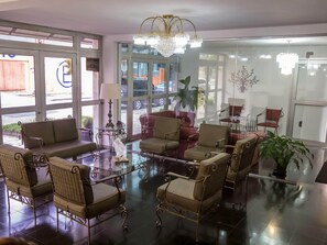 A lobby with a chandelier, seating area, and large windows. - Hotel Estrela do Sul (Curitiba)