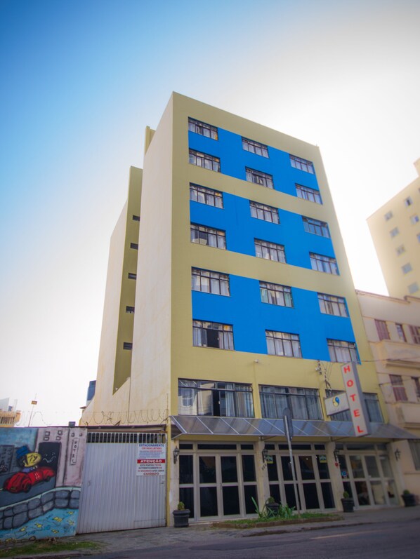 A multi-story hotel with a blue and yellow facade, large windows, and a gated entrance. - Hotel Estrela do Sul (Curitiba)