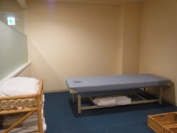 A small room with a single bed, a bench with a storage compartment underneath, and a wicker basket on the floor.
