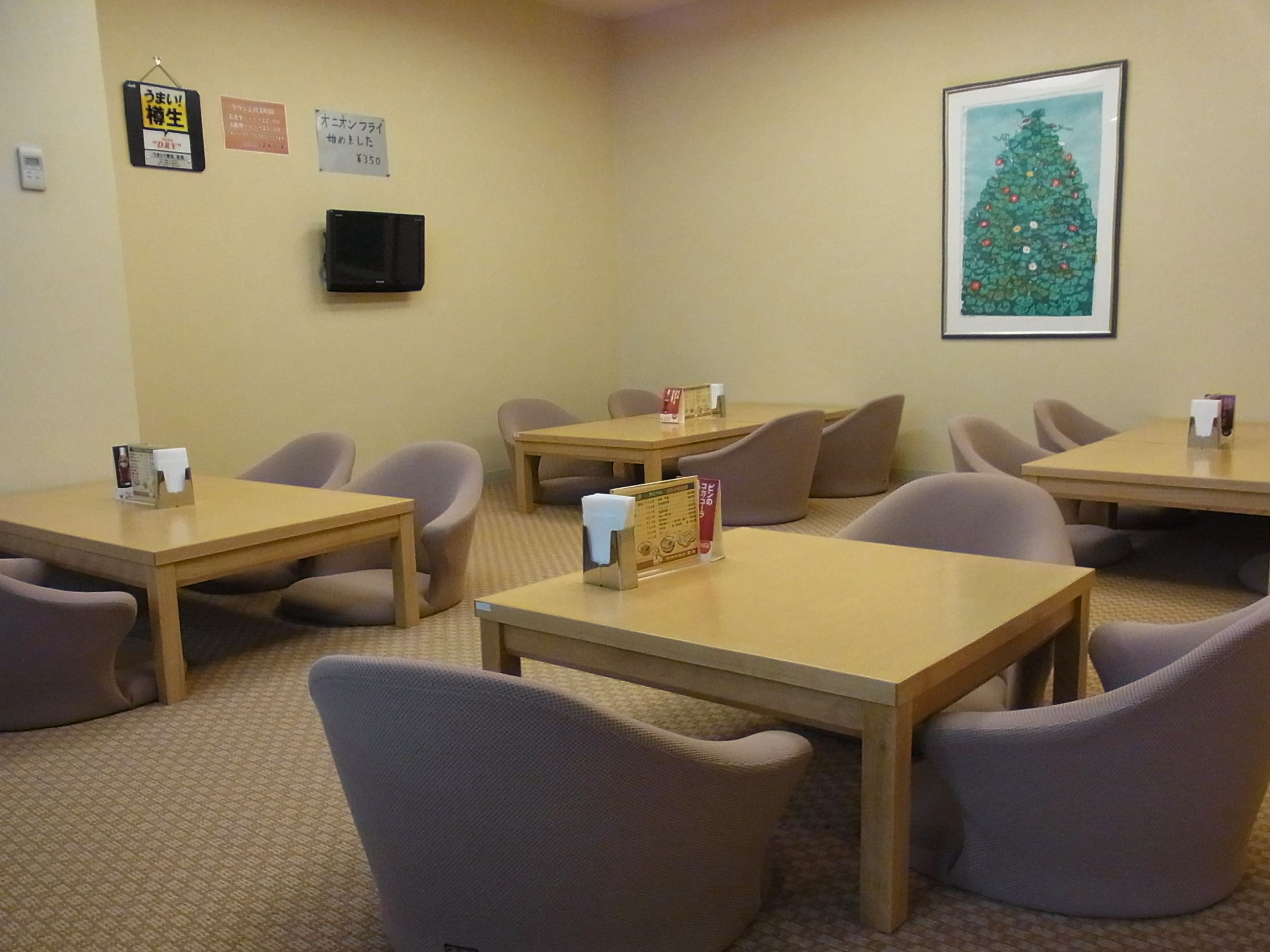 A conference room with tables and chairs, a clock, and a framed Christmas tree on the wall.