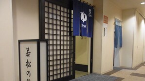 A hallway with a traditional Japanese sliding door, a mat at the entrance, and a sign with Japanese characters.