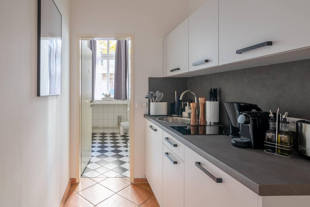 A modern kitchen with a black and white checkered floor, a coffee machine, and a sink.