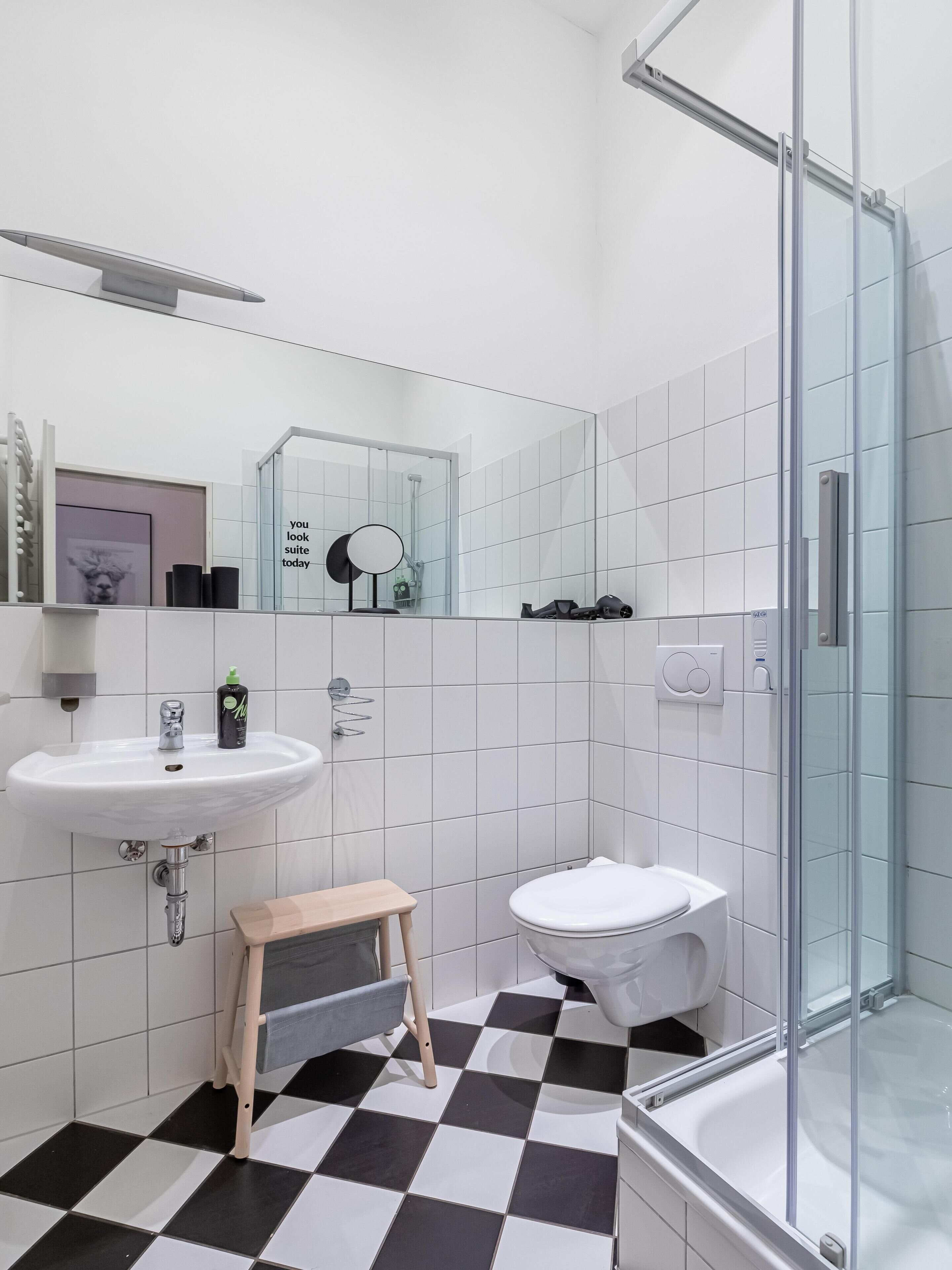 Une salle de bain moderne avec un lavabo, des toilettes et une douche, le tout de couleur blanche.