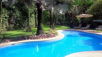 Una piscina al aire libre, sillones reclinables de piscina