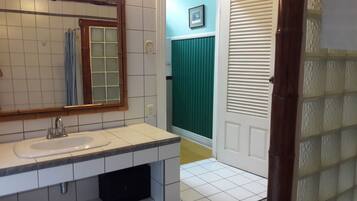 Een badkamer met een witte wasbak, spiegel en een groen douchegordijn.