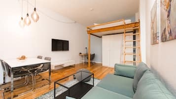 A modern living room with a bunk bed, a dining area, and a TV.