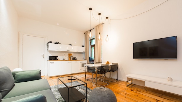 Ein modernes Wohnzimmer mit einer Couch, einem Couchtisch und einem an der Wand montierten Fernseher.