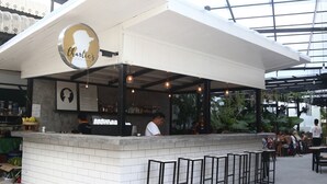 A restaurant with a white exterior and a glass roof, featuring a logo with a silhouette of a person and the name 'Charlie’s Kitchen & Bar'. - PP Princess Pool Villa (Ko Phi Phi)