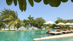 A clear pool with lounge chairs and umbrellas, surrounded by palm trees and a view of the beach. - PP Princess Pool Villa (Ko Phi Phi)