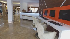 A reception area with a white counter, multiple computer stations, and a few bar stools. - Exelsior Annex (Marmaris)