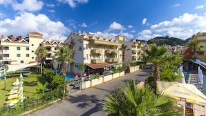 A hotel with multiple balconies, a swimming pool, and a garden area with palm trees. - Exelsior Annex (Marmaris)