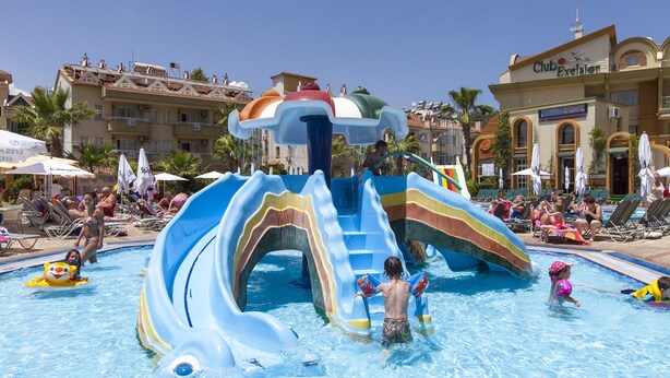 A pool area with a water slide and lounge chairs. - Exelsior Annex (Marmaris)