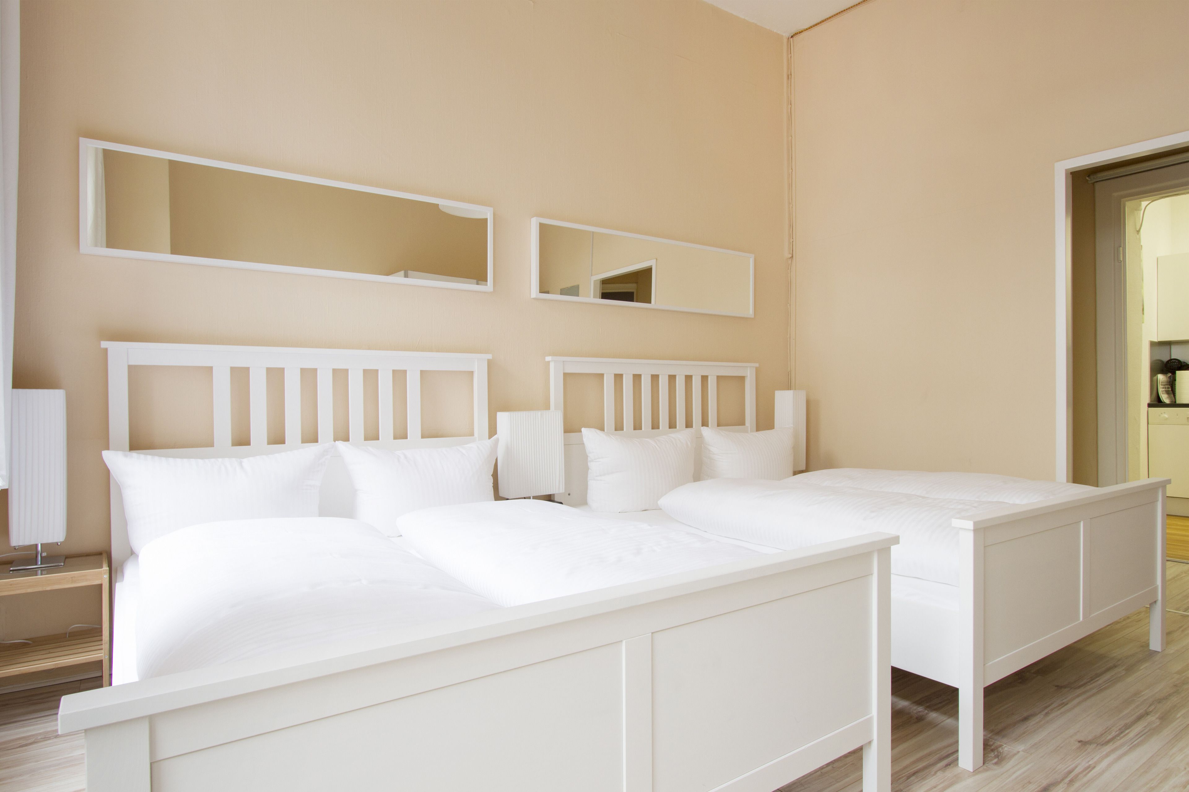 A bedroom with a double bed, two bedside tables, and two wall-mounted mirrors.