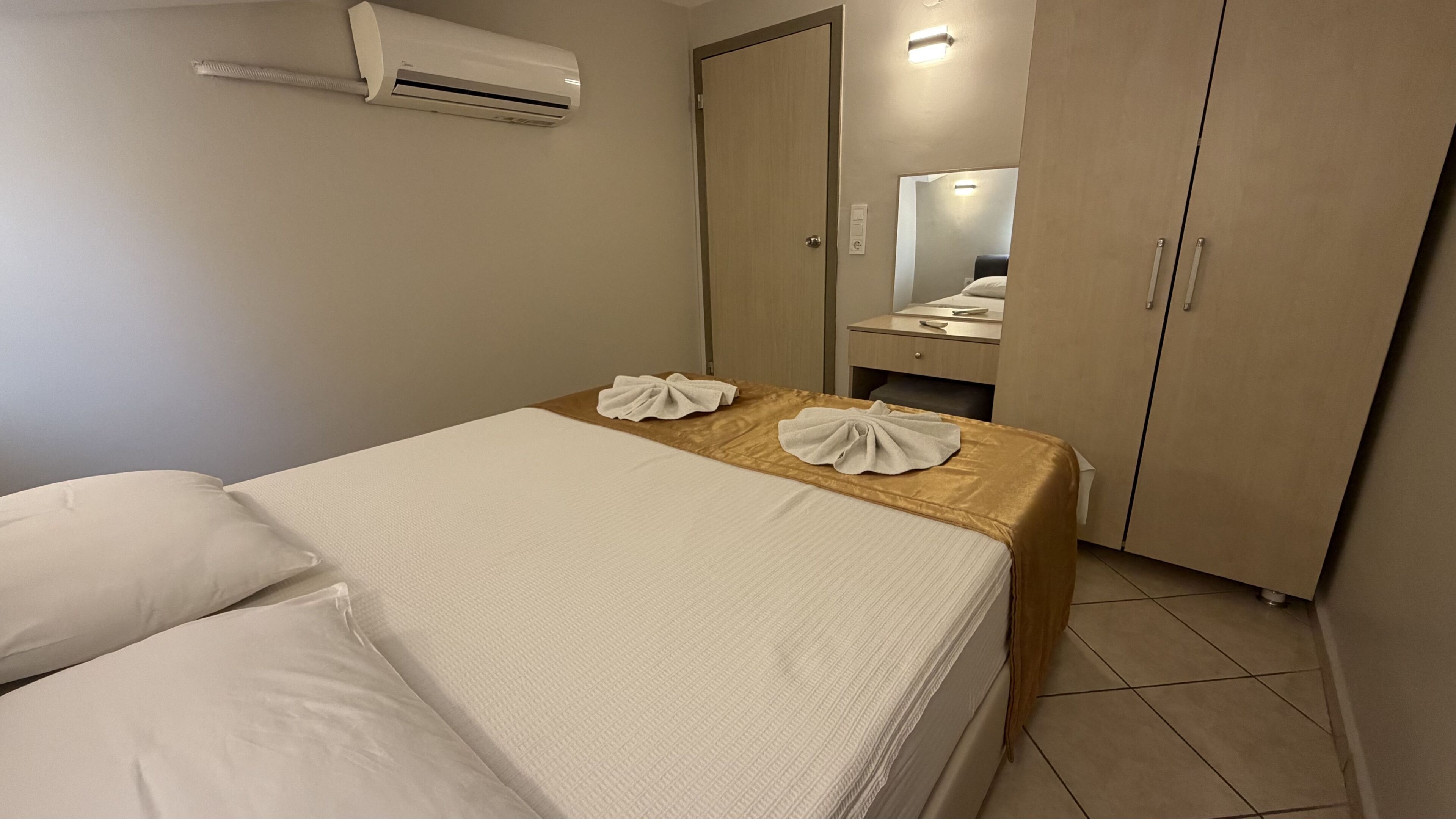 Une chambre d’hôtel équipée d’un lit, d’une table de chevet, d’un miroir, d’une armoire et d’un appareil de climatisation.