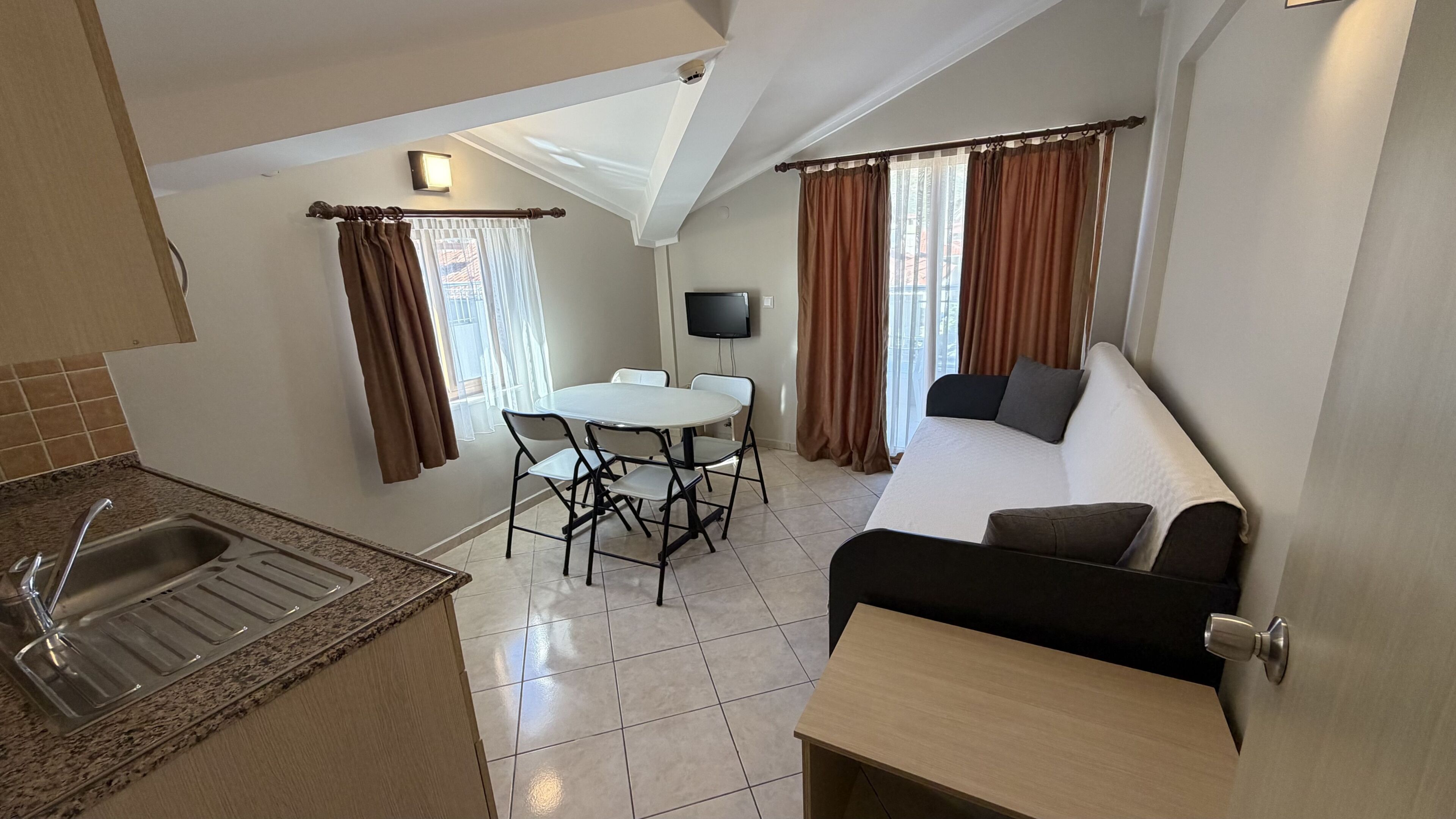 A compact living space with a kitchenette, dining area, and seating area.