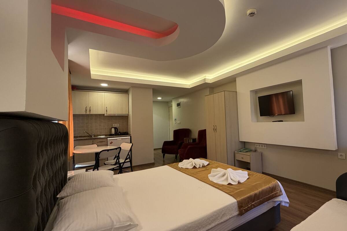 A hotel room with a bed, a desk, a chair, a TV, and a wardrobe.