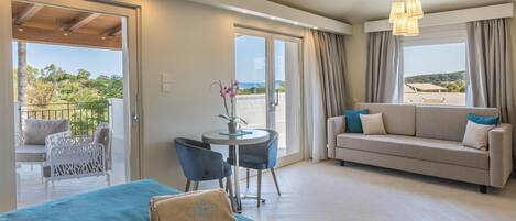 Habitación de hotel con balcón, sofá, mesa con sillas y cama con toalla azul.