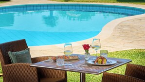 Un espace repas aménagé au bord de la piscine, avec une table pour deux, offrant une vue sur la piscine et un paysage pittoresque de collines et de verdure.