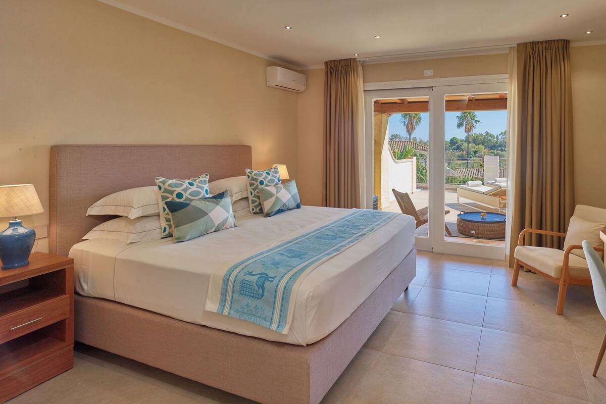 Een hotelkamer met een groot bed, een bureau, een stoel en een balkon met uitzicht.