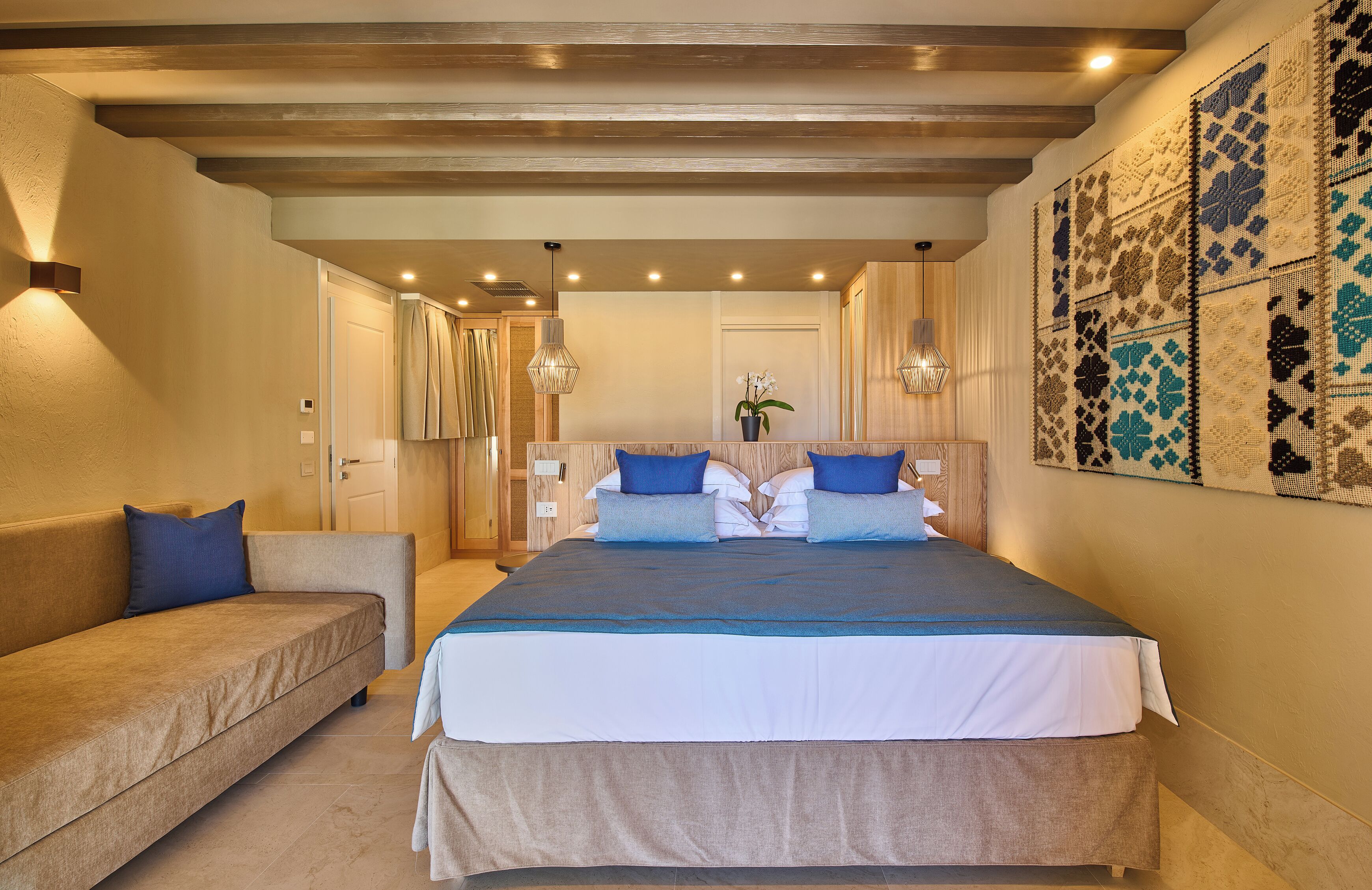 A bedroom with a large bed, a sofa, and a decorative wall.