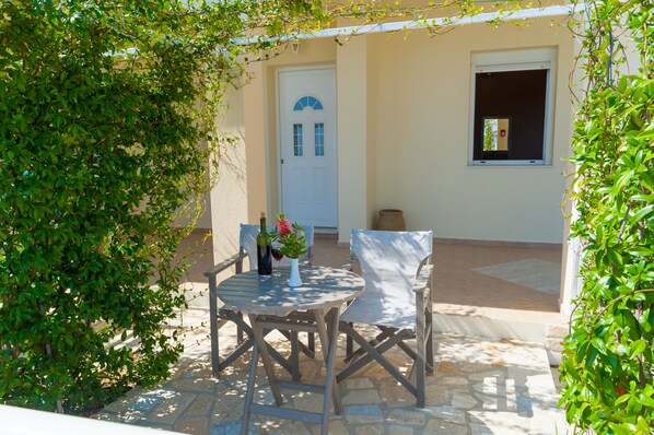 An outdoor patio with a table and chairs, a door, and a window. - Valta View Suites & Apartments (Kefalonia)