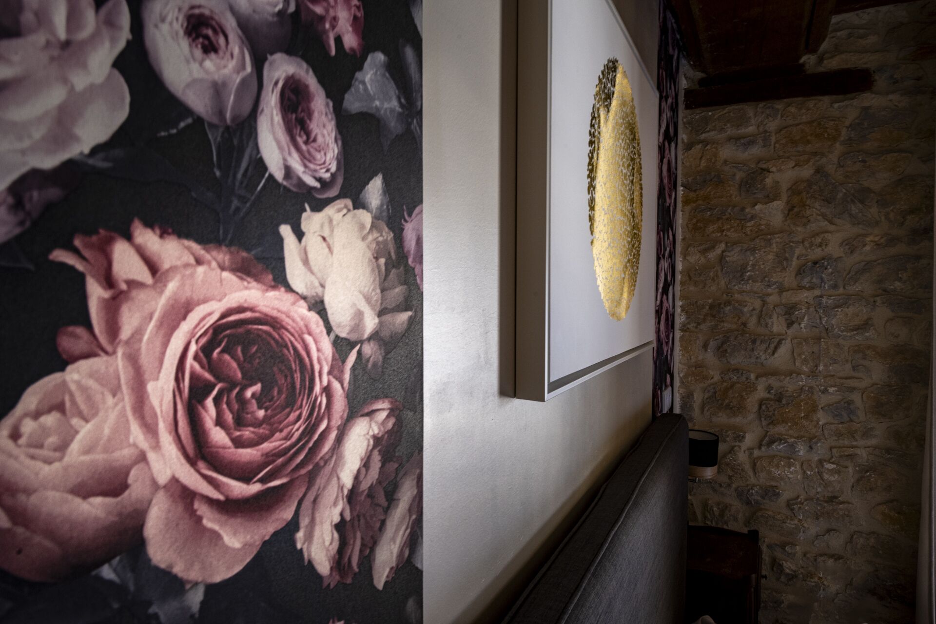 Un mur recouvert d’un papier peint à motifs floraux et orné d’une œuvre d’art encadrée.