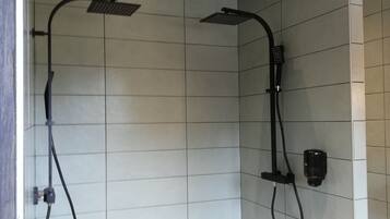 Un baño moderno con dos cabezales de ducha, un lavabo blanco y un espejo.