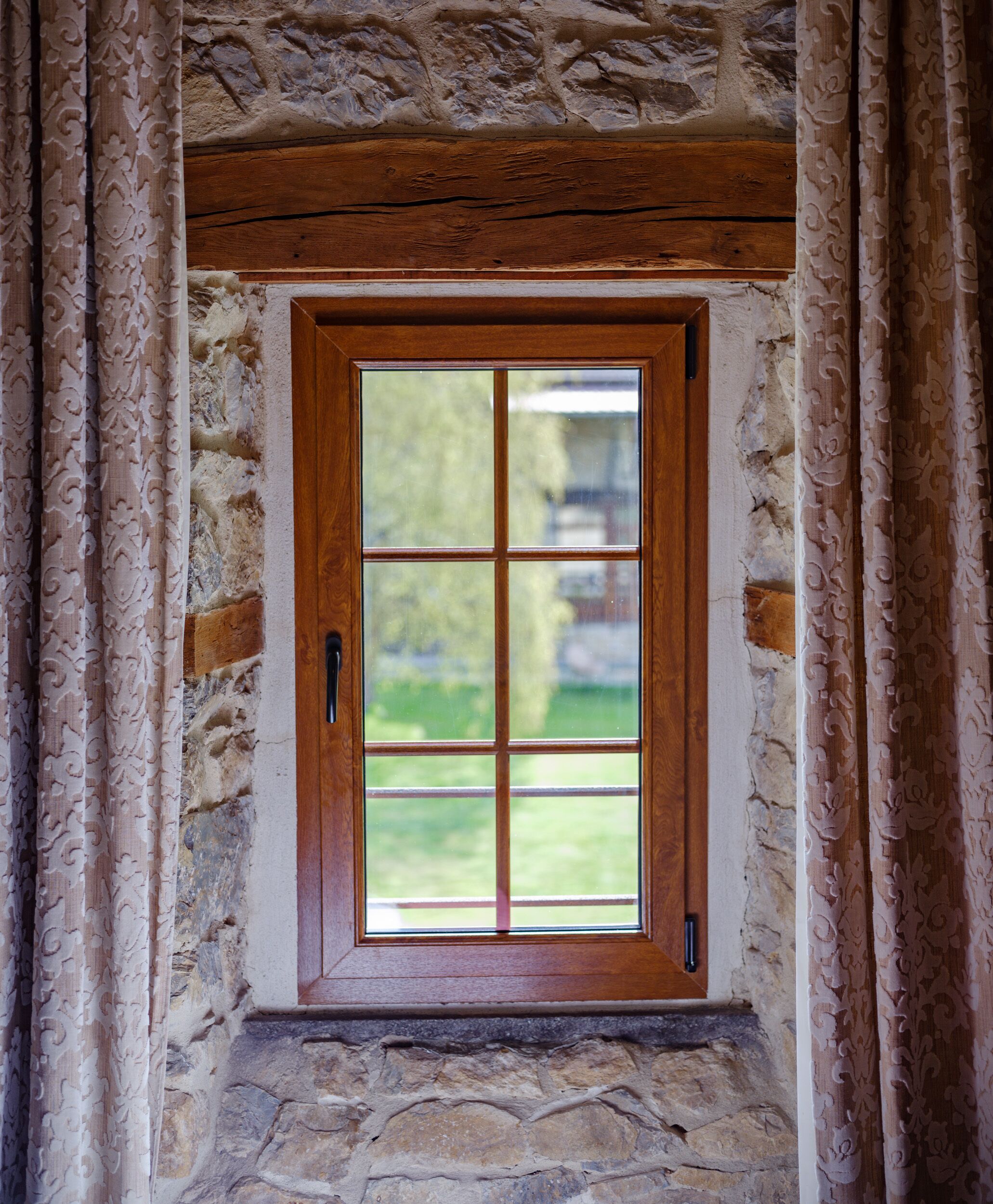Une fenêtre à cadre en bois, avec un mur en pierre et un petit rebord de fenêtre.