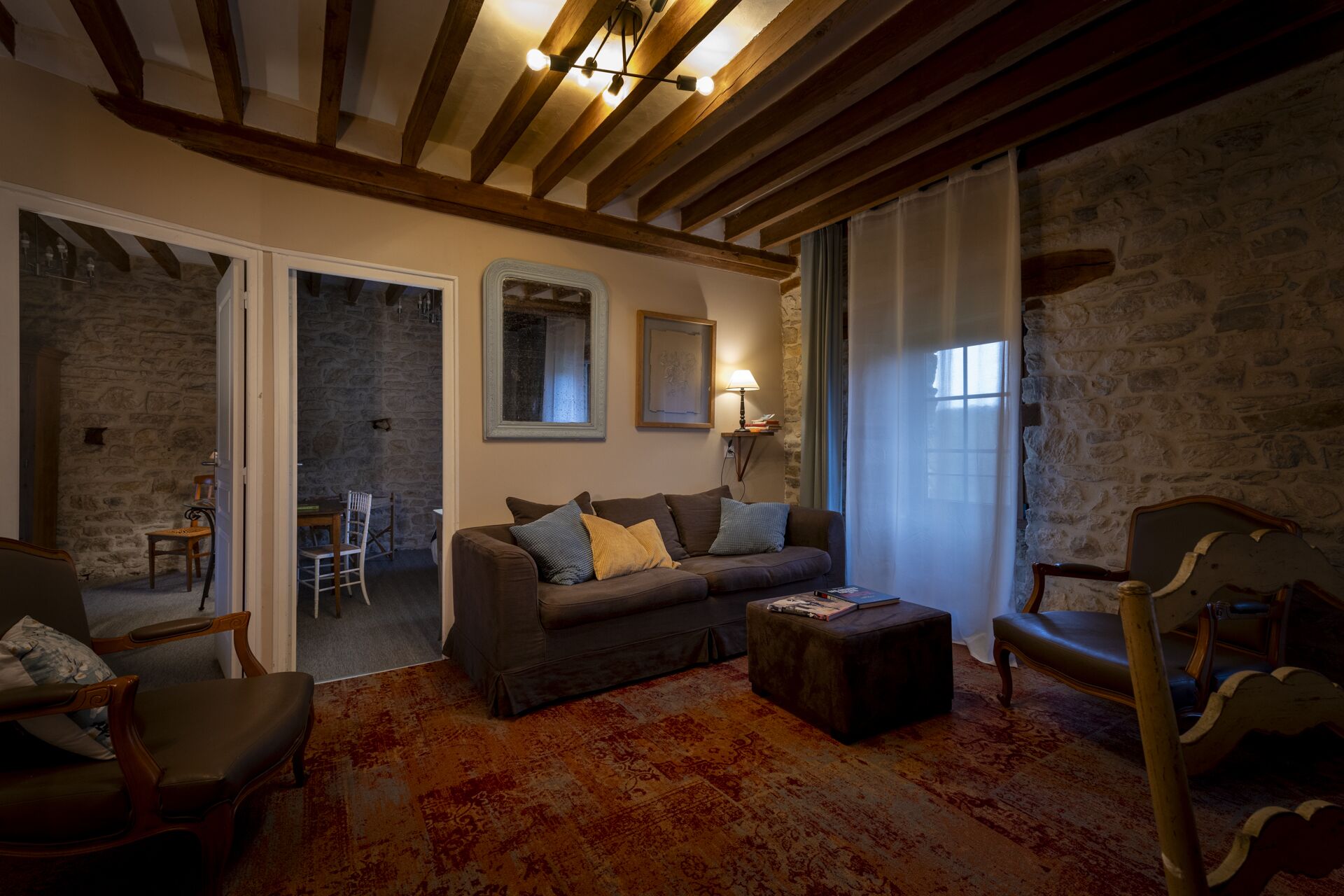 Un salon chaleureux avec un canapé, des fauteuils, une table basse et un mur en pierre.